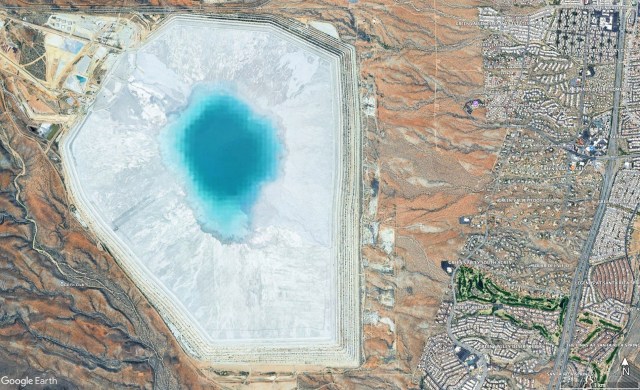 A satellite image of a tailings pond. From this altitude the pond appears as a large white mass with a bright blue water feature at the center.